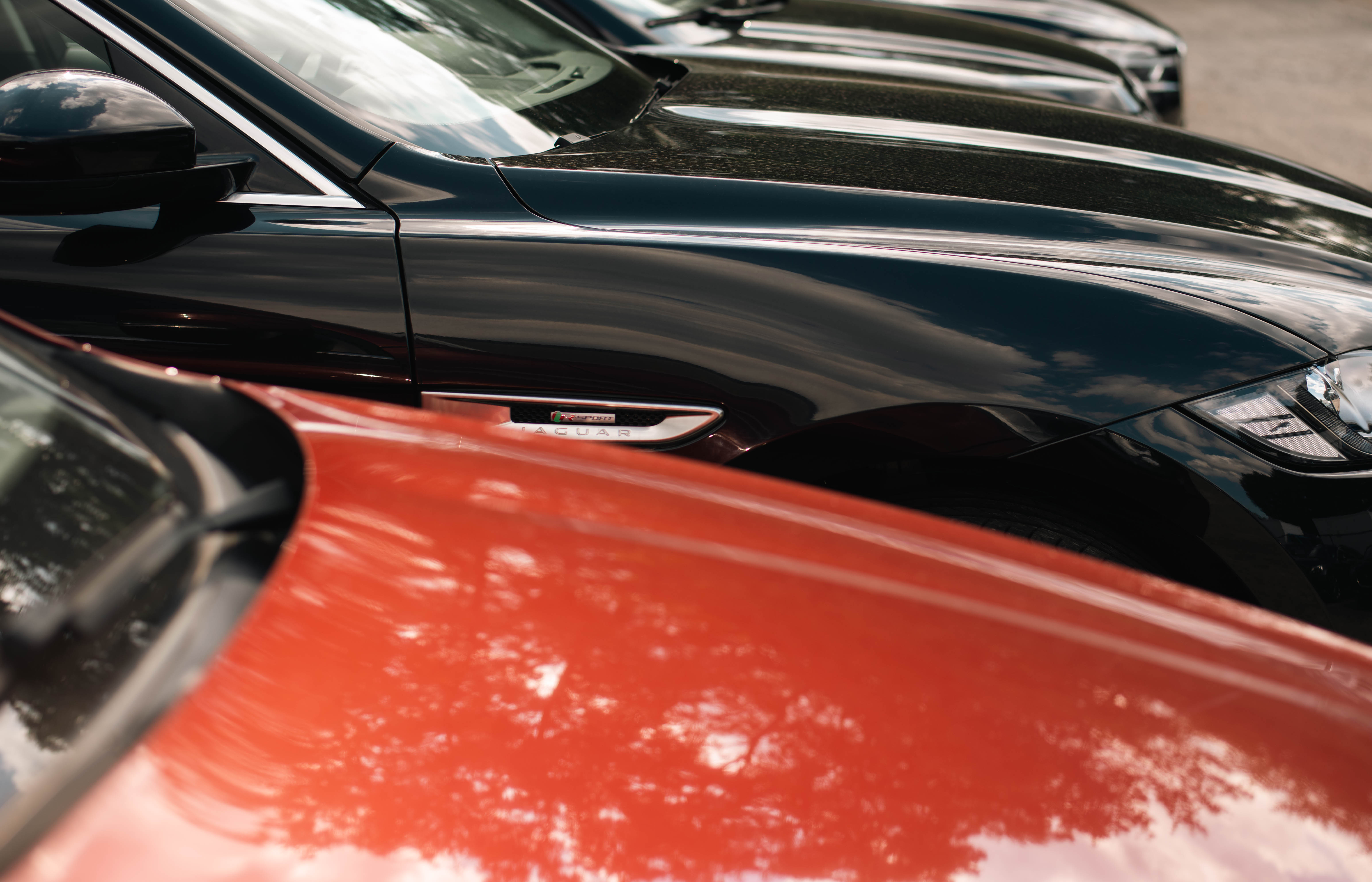 close up of a red car and black Jaguar parked on eCarsTrade parking